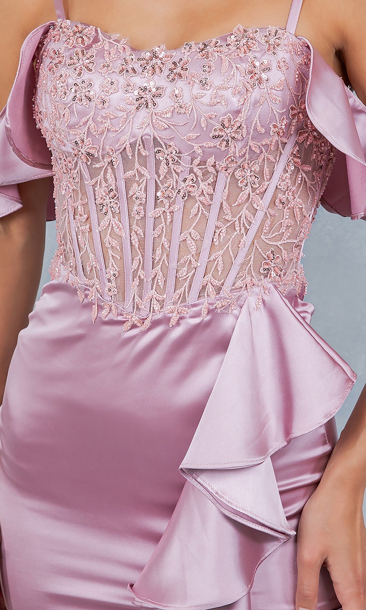 A woman wears the Long Prom Dress: Cinderella Couture 8461J in light pink, featuring a form-fitting silhouette, embroidered corset bodice with beaded floral details, sheer panels, and satin ruffle accents at the waist.